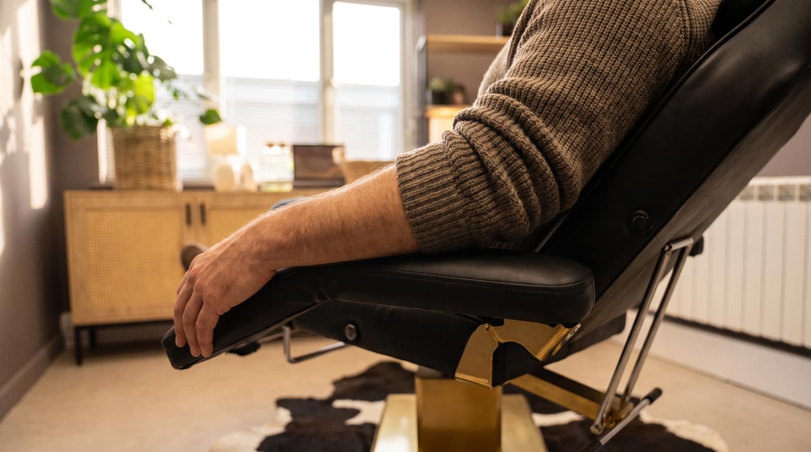 A hand and forearm resting on the arm of the treatment chair at Kennedy SMP Studio in Haverhill, on a calm autumn morning