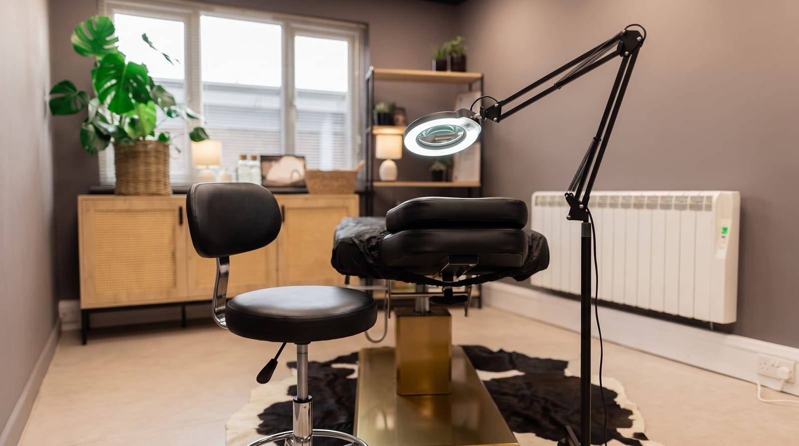 The magnifier lamp and practitioner stool set up over the treatment chair for the precise detail work of density scalp micropigmentation at Kennedy SMP Studio