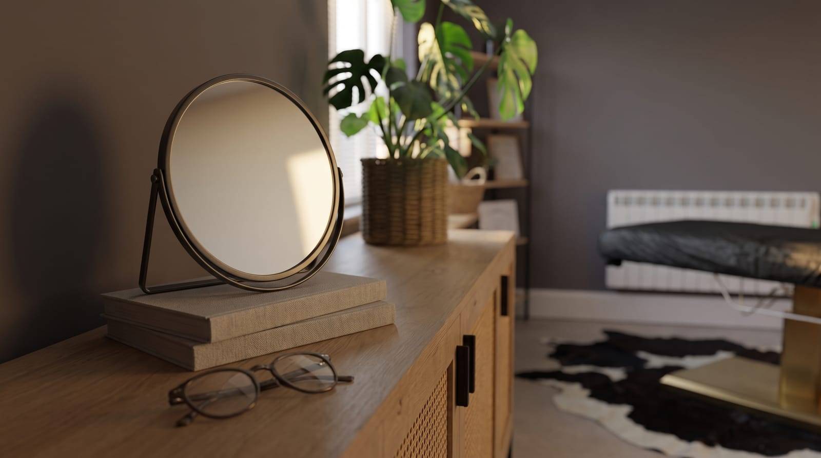 A round hand mirror propped upright on a stack of books beside a folded pair of reading glasses, catching soft daylight, the quiet setup for checking a hairline properly rather than glancing at it