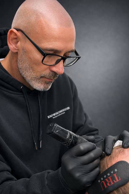 Stephen Kennedy, scalp micropigmentation practitioner at Kennedy SMP Studio, holding a micropigmentation machine